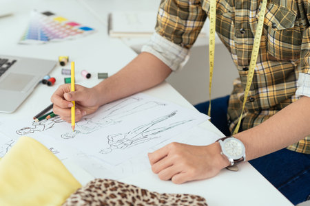 Unrecognizable fashion designer drawing sketches in his workshopの写真素材