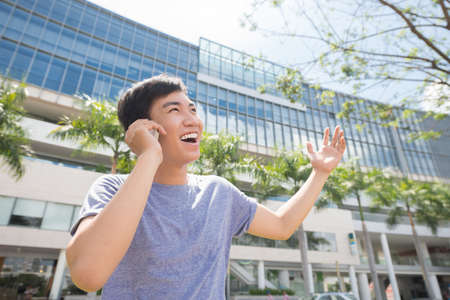 Asian man having emotional phone conversation outdoorsの写真素材