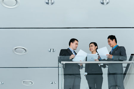 Three business colleagues discussing papers while standing on the balcony