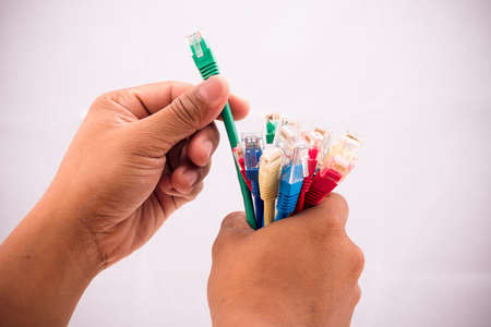 Hand selecting green internet cable from the set of different onesの写真素材