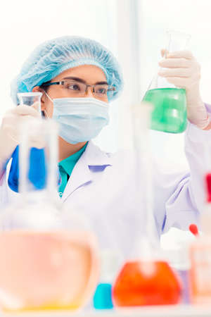 Young laboratory working looking at flask in her handの写真素材