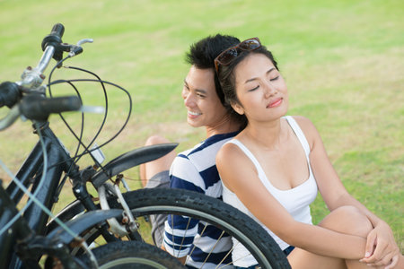 Couple with bikes relaxing on the meadowの写真素材