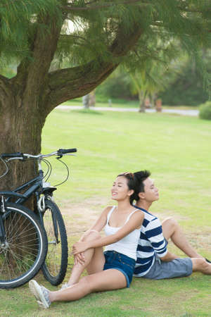 Young couple relaxing under the tree after bikingの写真素材