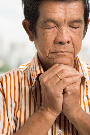 Vietnamese elderly man praying with his eyes closedの写真素材