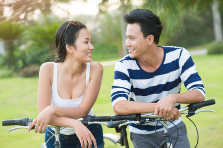 Young couple on bicycles smiling and looking at each otherの写真素材