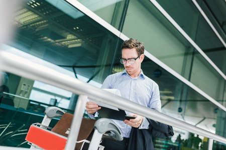 Businessman in glasses reading a customs declaration at the airportの写真素材