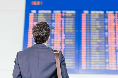 Man looking at the timetable in the airport, view from the backの写真素材