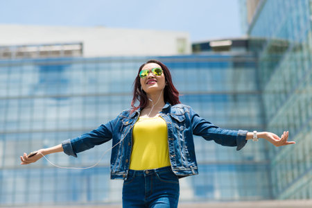 Young woman enjoying music in her earphones while standing outdoorsの写真素材