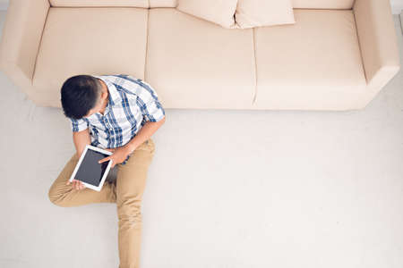 Man sitting on the floor with digital tablet, view from the topの写真素材