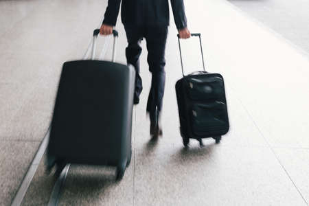Unrecognizable man with two suitcases hurryingの写真素材