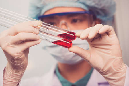 Researcher looking the test tubes with blood analysisの写真素材