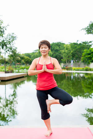 Senior woman standing in yoga pose on one legの写真素材
