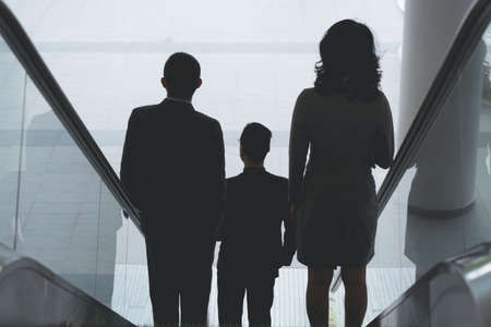 Business people going down the escalator, rear viewの写真素材