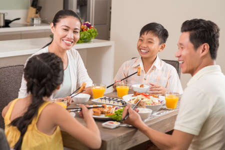 Happy Vietnamese family laughing while having dinnerの写真素材