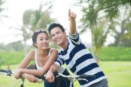 Young man pointing at something while standing in the park with his pretty girlfriendの写真素材