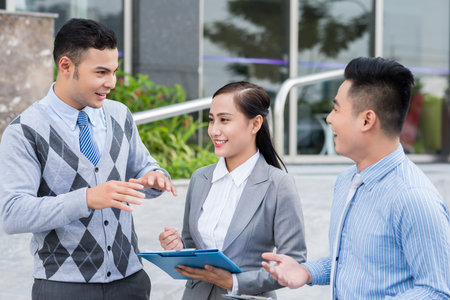 Young cheerful managers having discussion outdoorsの写真素材