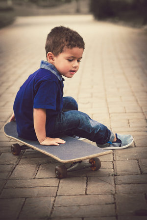 Portrait of little kid sitting on the skateboardの写真素材