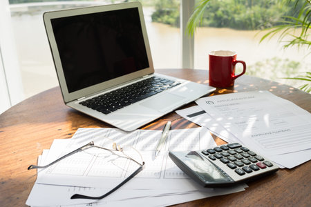 Workplace of accountant: laptop, documents, calculator, glasses and coffee cupの写真素材