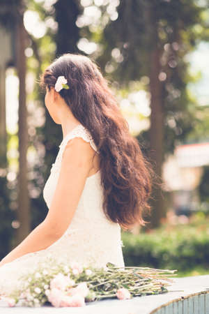 Woman with a flower in her hair sitting on the benchの写真素材