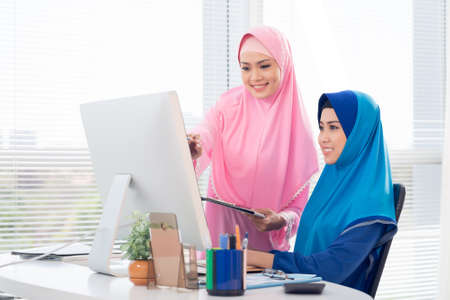Business colleagues in hijabs looking at the computer monitorの写真素材