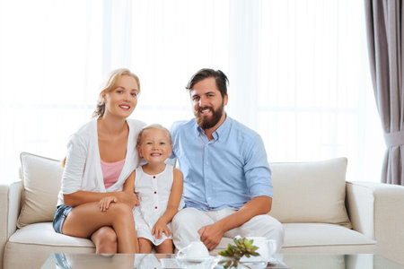 Portrait of happy family sitting on the sofa and looking at the camera