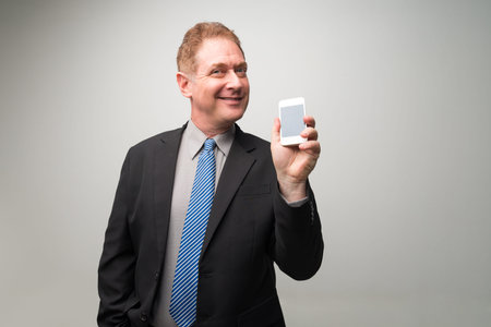 Happy mature manager displaying smartphoneの写真素材