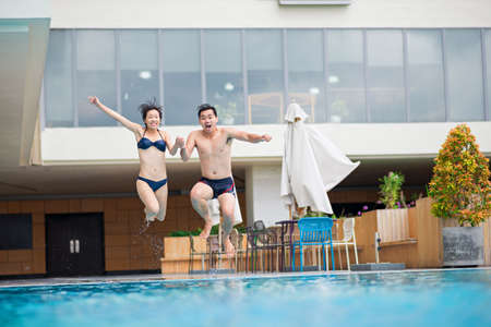 Young Vietnamese couple jumping into the swimming poolの写真素材