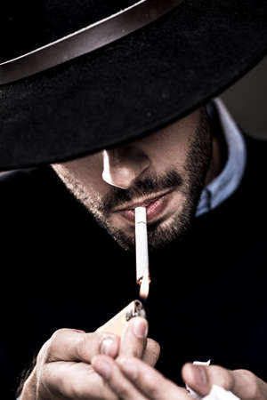 Man in hat lightning  a cigaretteの写真素材