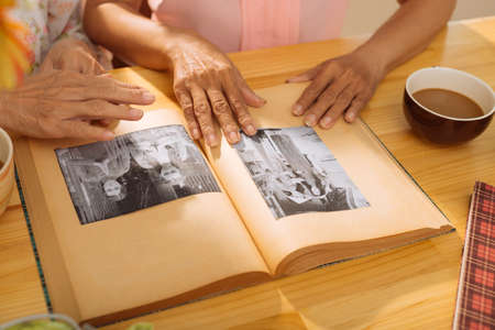 Hands of mature women watching old photos in theの写真素材