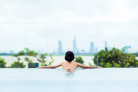 Woman enjoying the city view from infinity poolの写真素材