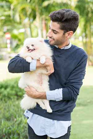 Young Hispanic man holding his little dogの写真素材