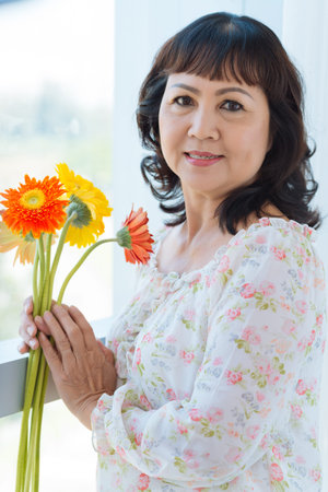 Beautiful mature woman with a bouquet of flowersの写真素材
