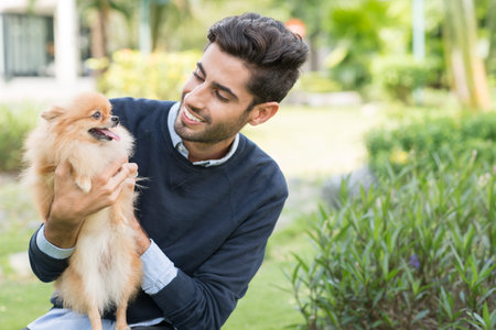 Smiling man looking at Pomeranian spitz in his handsの写真素材