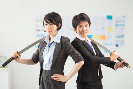 Japanese businesswomen posing with katanasの写真素材