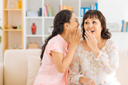 Mature woman telling a secret to her surprised friendの写真素材