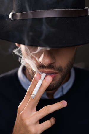 Man in a hat smoking cigaretteの写真素材
