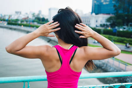 Rear view of sportswoman standing with her hands behind head showing upper-body musclesの写真素材