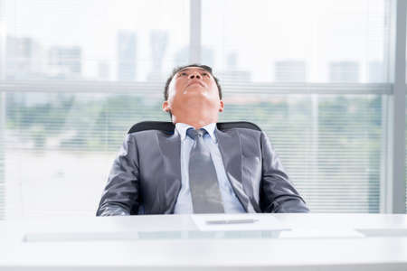 Businessman sitting tired in his chairの写真素材