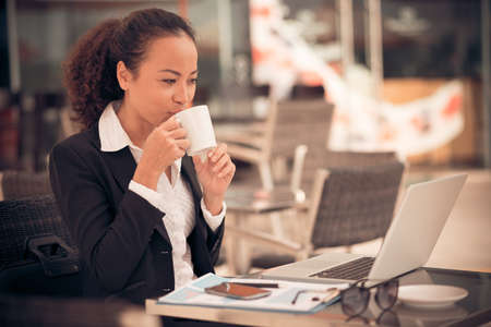 Business lady drinking coffee and working on laptop in the cafeの写真素材
