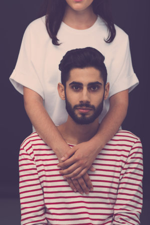 Portrait of handsome man, his girlfriend embracing him from behindの写真素材