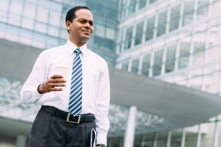 Portrait of Indian businessman with a cup of coffee outdoorsの写真素材