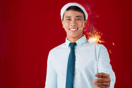 Young businessman in Santa hat holding a Bengal lightの写真素材