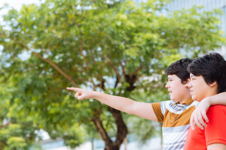 Young boy hugging his brother and pointing awayの写真素材