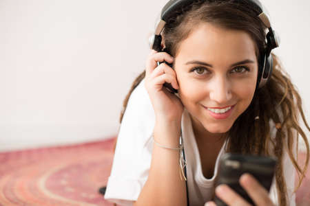 Cheerful girl listening to the music and looking at the cameraの写真素材