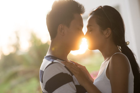 Side view of couple kissing while on the background of declining sunの写真素材