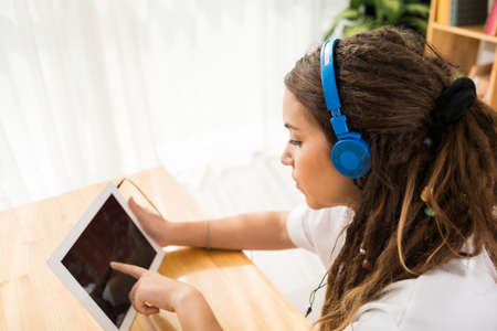 Teenage girl in headphones using a digital tabletの写真素材