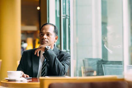 Portrait of pensive Indian businessman in the cafeの写真素材