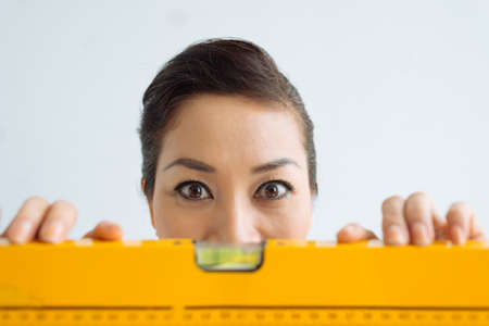 Woman with a spirit level staring wide-eyed at the cameraの写真素材