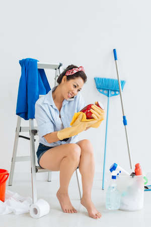Cheerful housewife talking on the phone while wiping a vaseの写真素材