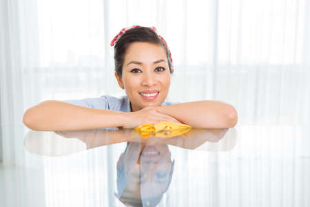 Portrait of happy Vietnamese housewife leaning on the tableの写真素材